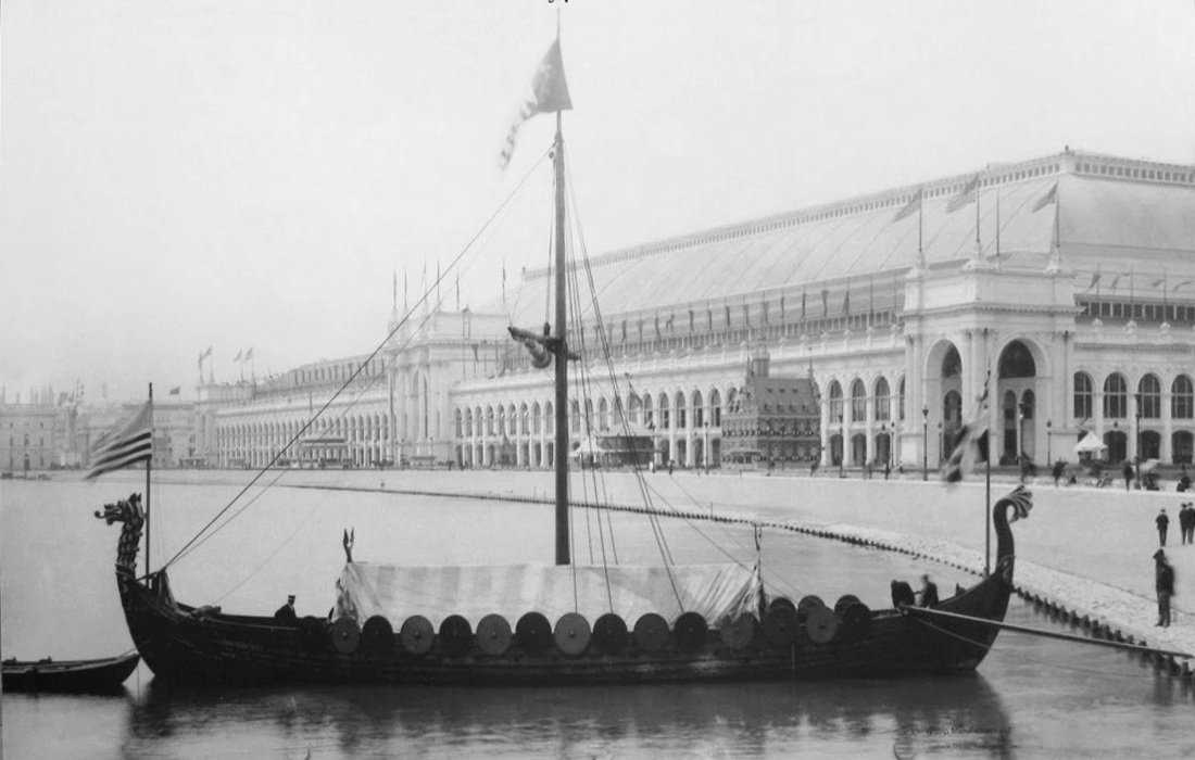 A viking longboat with a dragon's head mast and shields on the sides