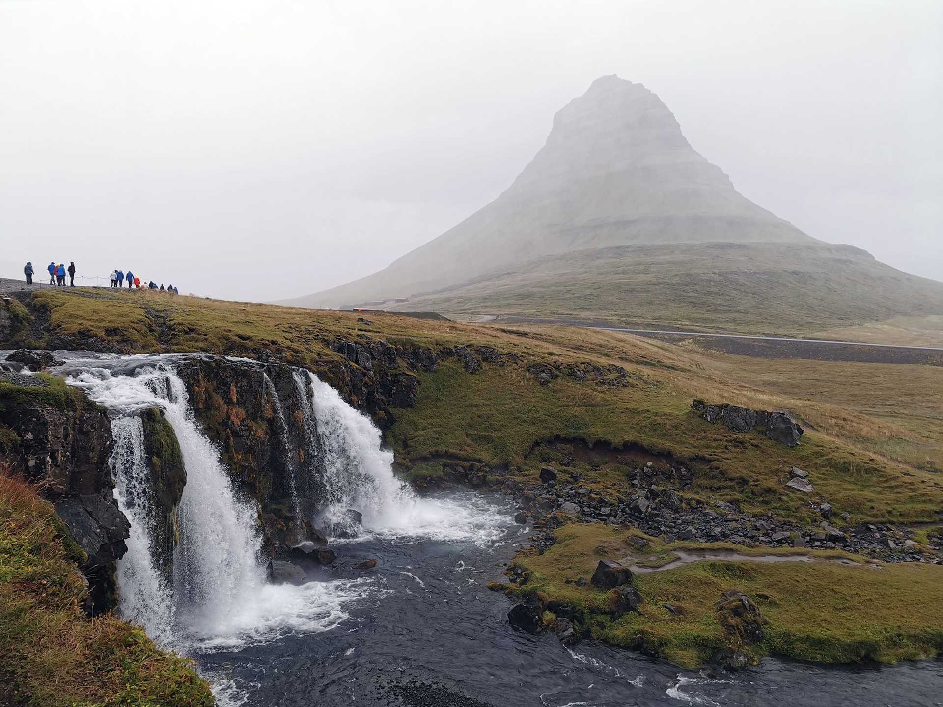 a waterfall in the foreground, with Kirkjufell mountain in the background