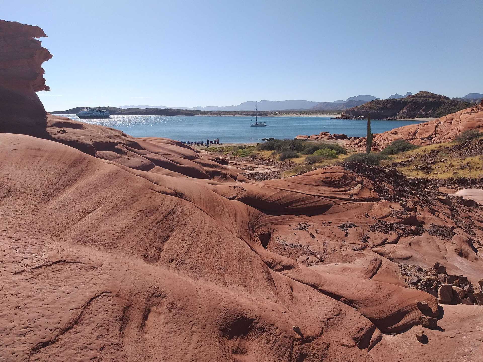 red rock landscape with ocean in background