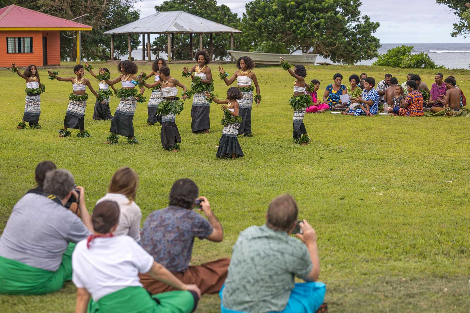 a dozen teenage girls in traditional Fijian costume perform a dance