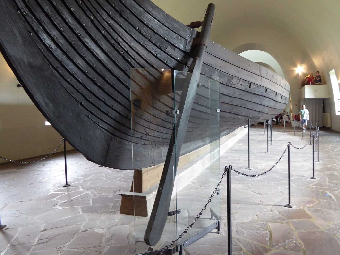 A dark brown wooden viking ship on display in a musem