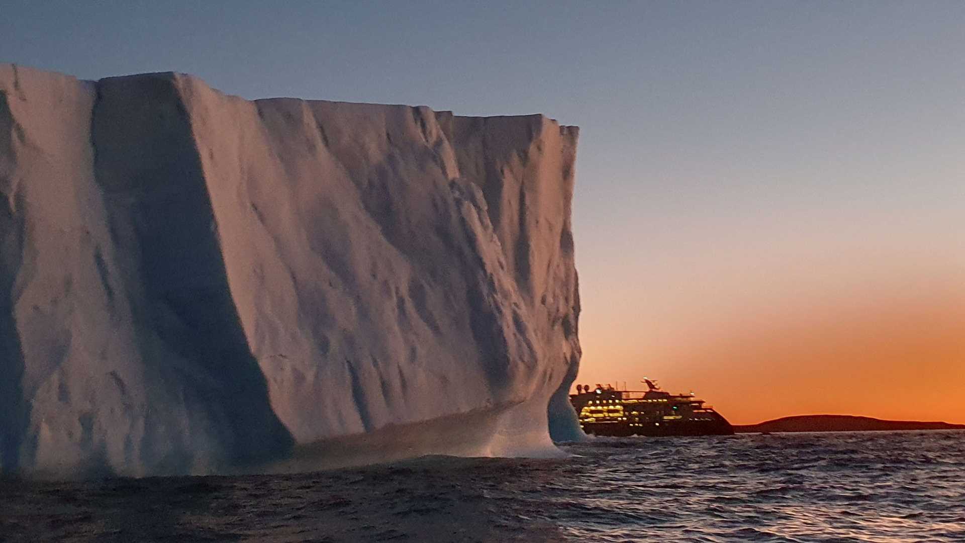 ship and giant iceberg at sunset