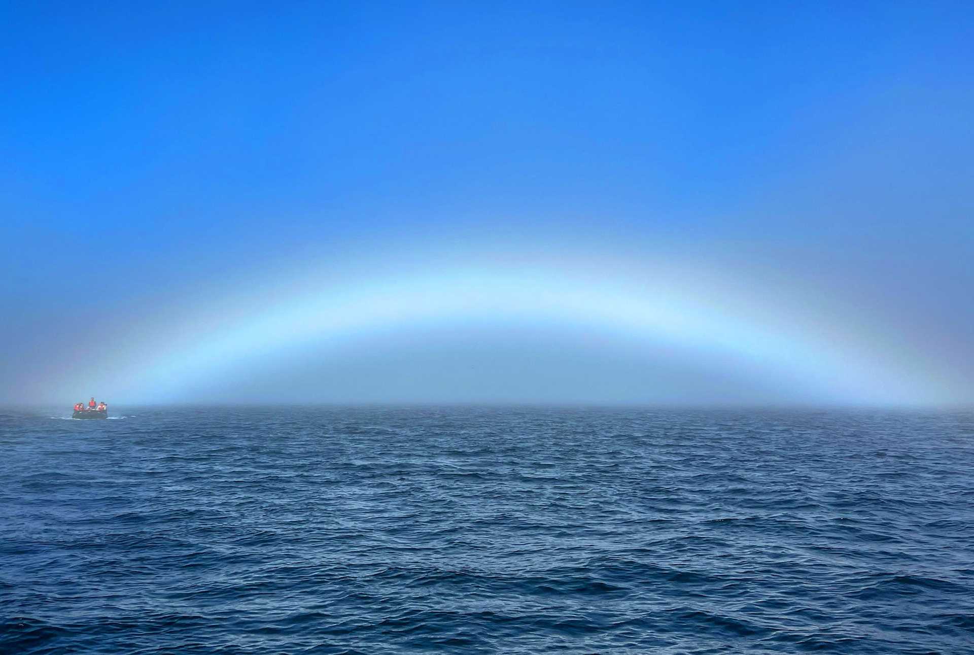 a foggy rainbow over water
