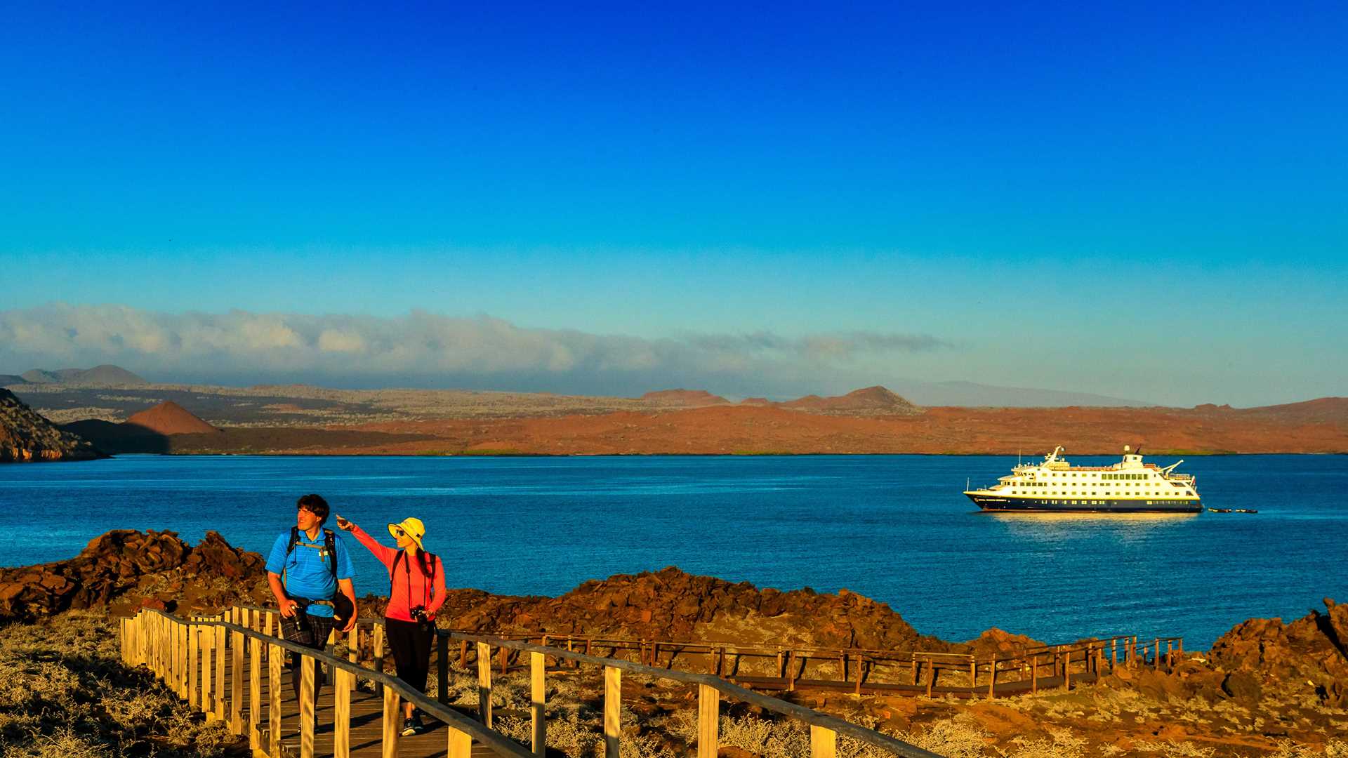 A man and a woman hike on a wooden path up Pinnacle Rock on Bartolome Island, Galápagos.