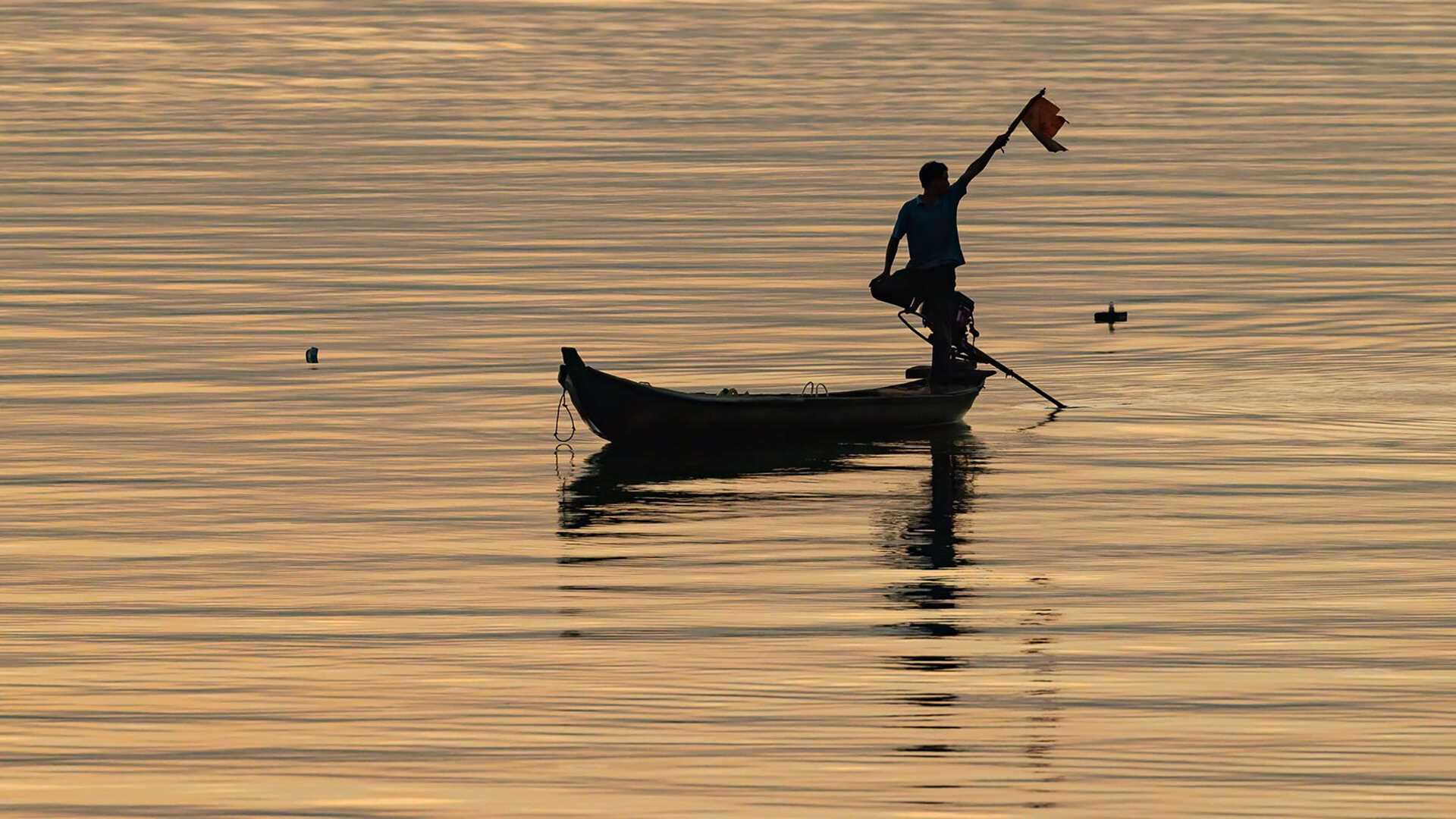 a fisherman silhouetted at sunset