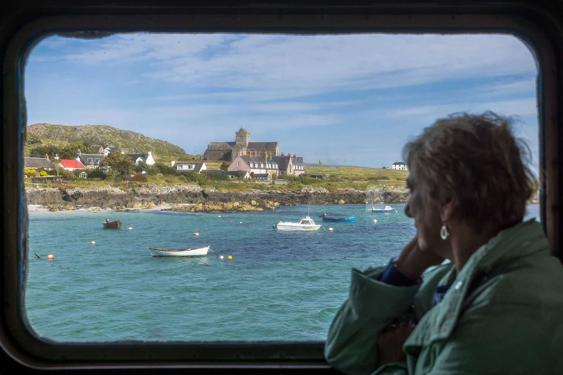 a woman looks out the window of the ship at Iona, Scotland