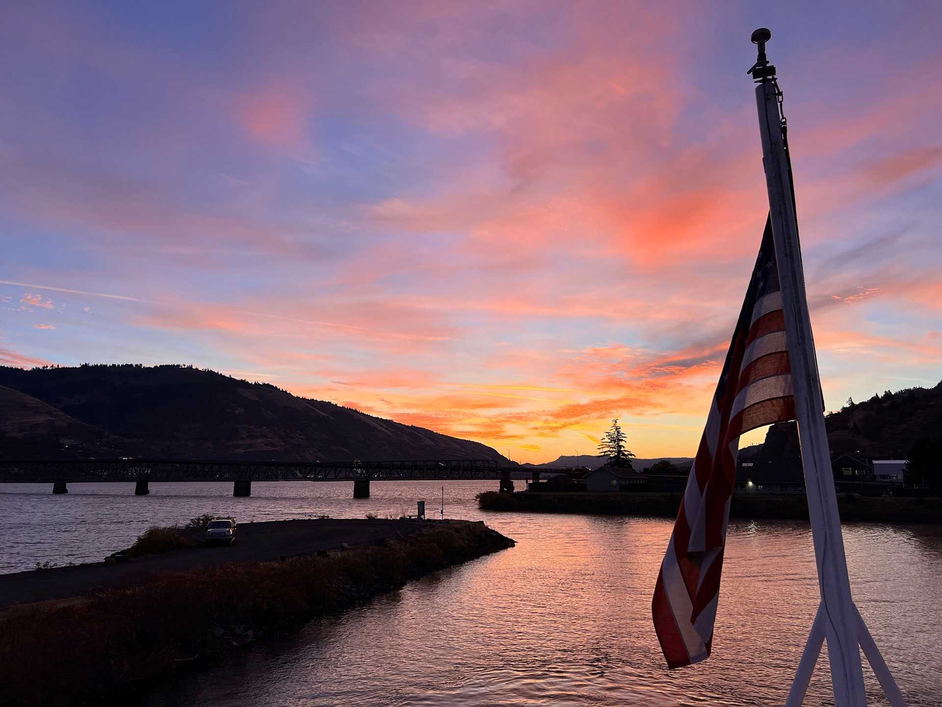 a colorful sunrise with an american flag in the foreground