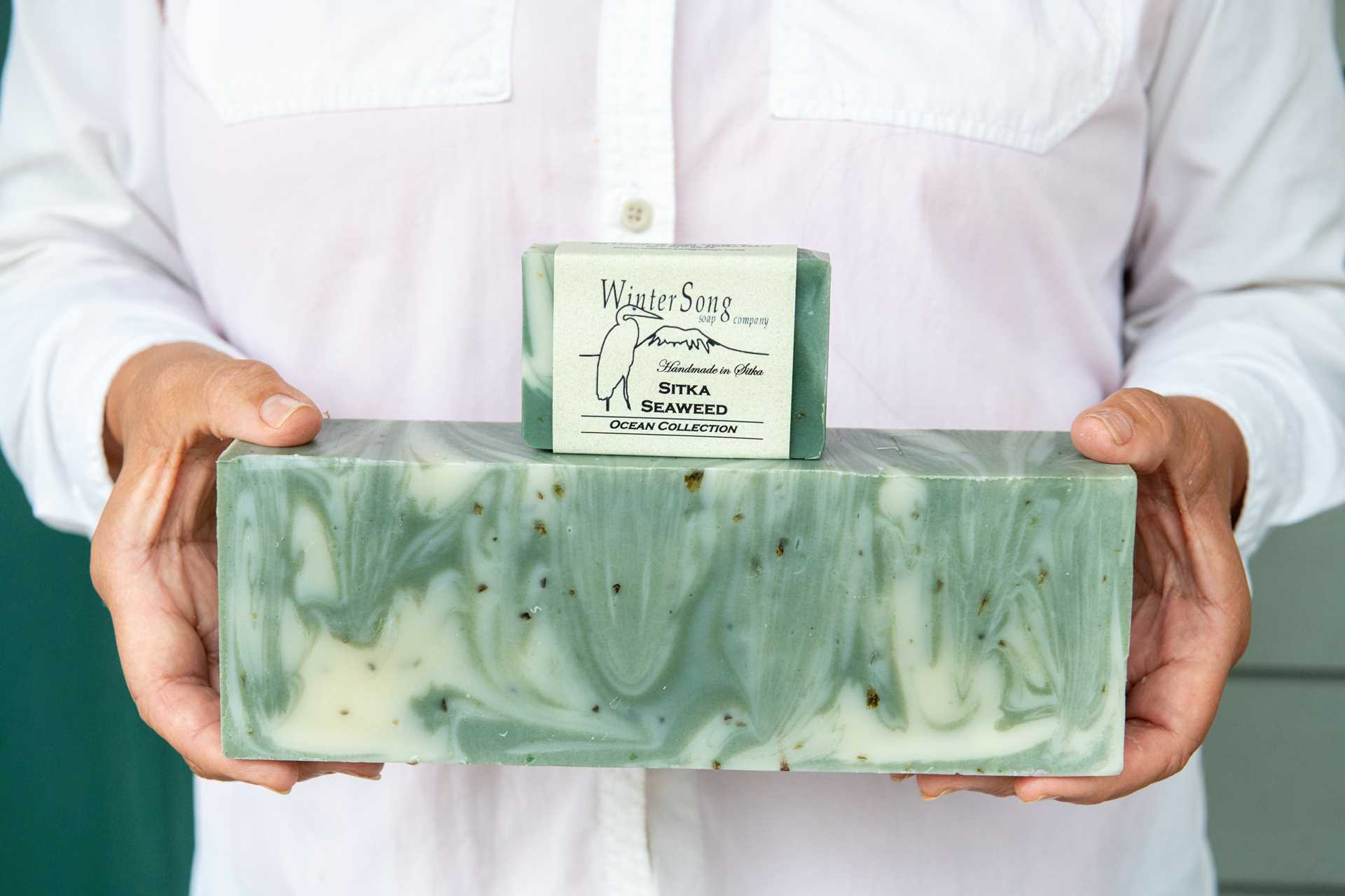 A woman holds a block of Sitka seaweed soap.