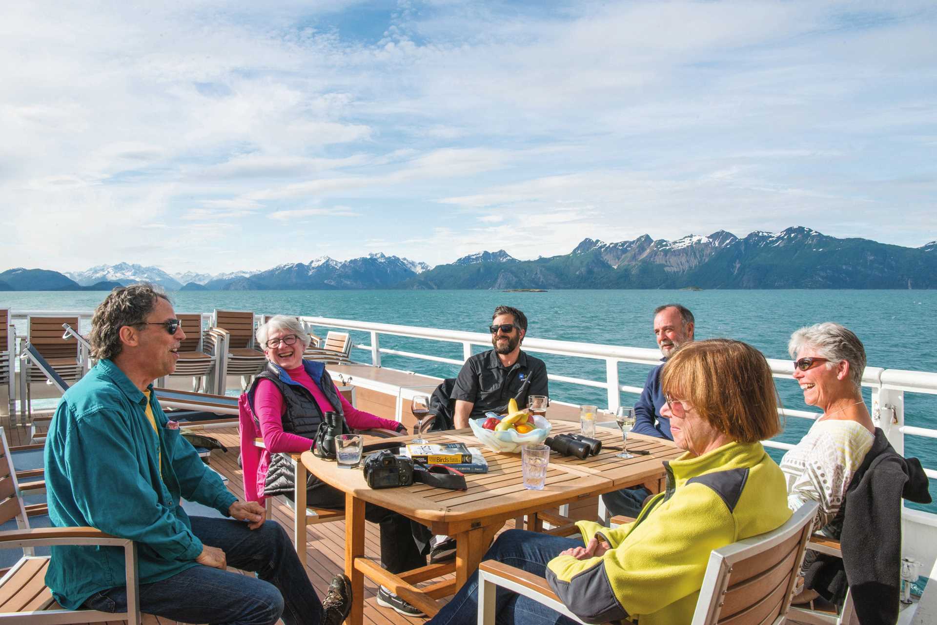 Guests sit and talk on the open deck of the National Geographic Sea Bird in Alaska.