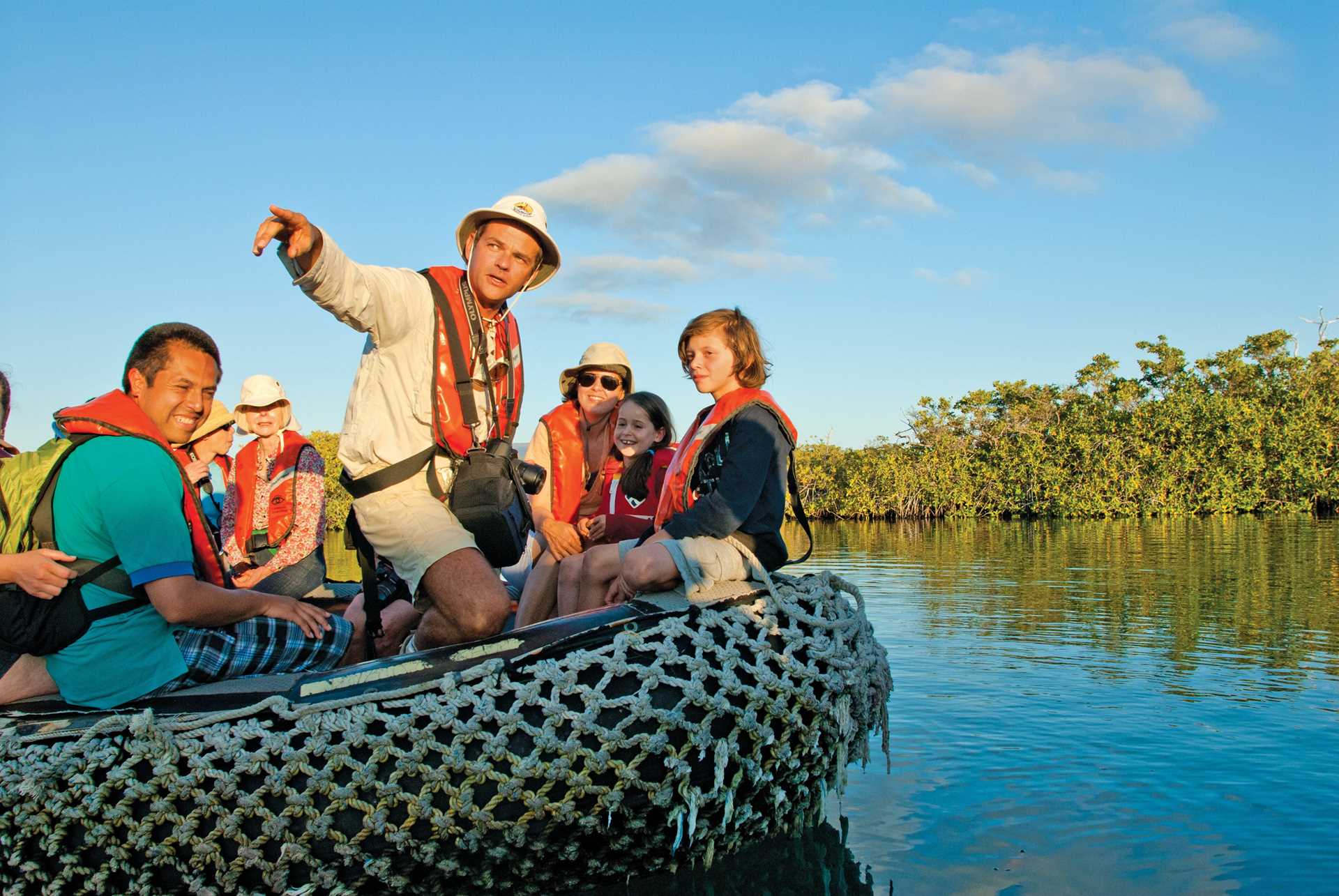 A naturalist points something out to a family of travelers on a Zodiac.