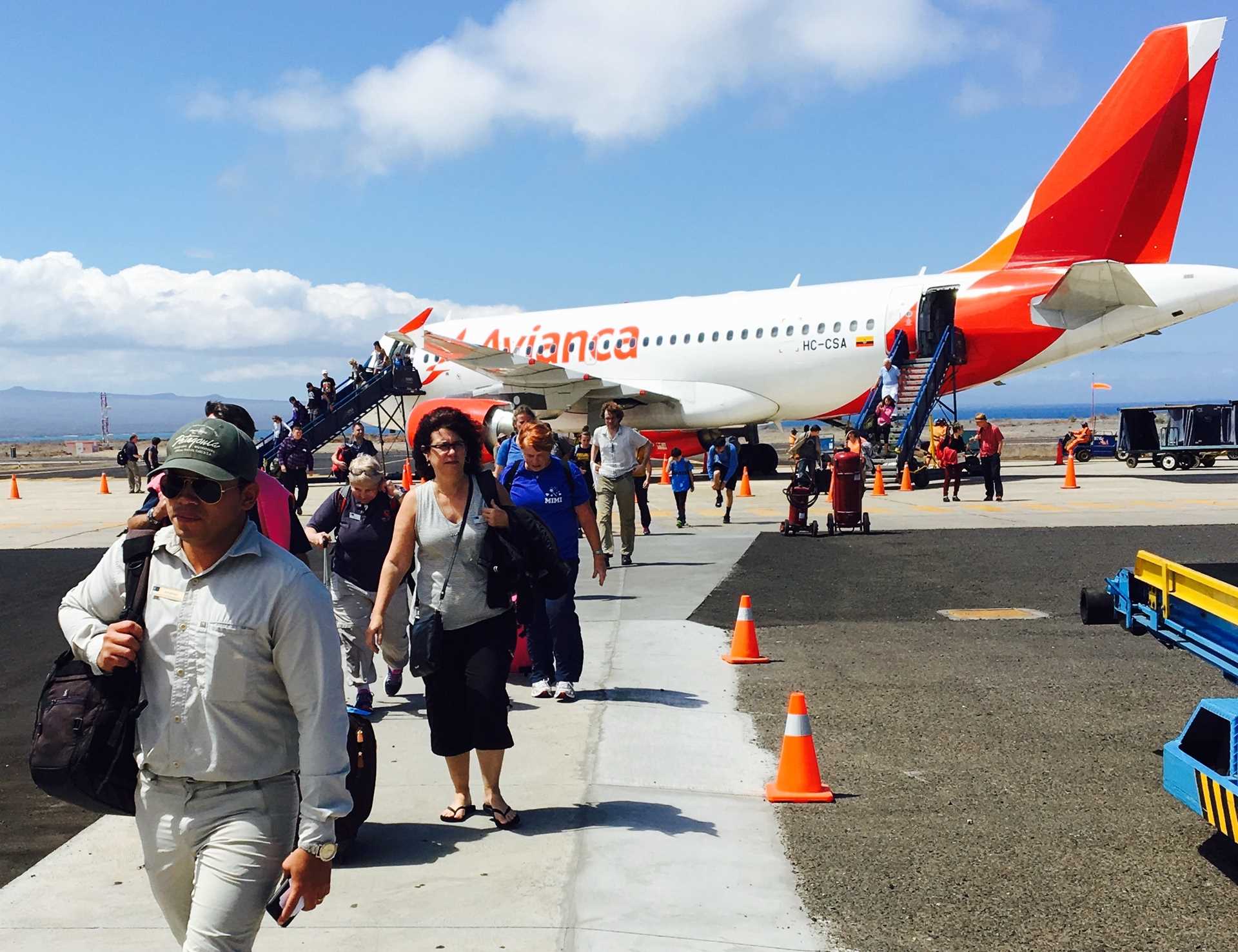 Guests and naturalist disembark an airplane on the tarmac at Seymour Galápagos Ecological Airport, Baltra Island.